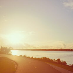 Curved road next to lake under horizon.